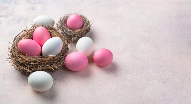 Oeufs pastel rose et blanc dans un nid et sur un fond clair Vue latérale de l'espace de copie Le concept d'une Joyeuses Pâques