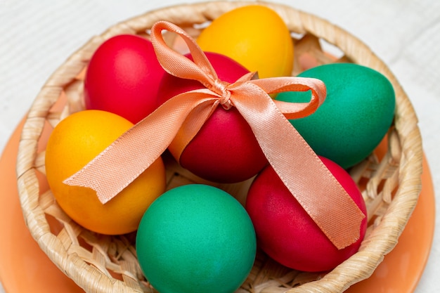 Oeufs peints colorés avec noeud pour Pâques dans un panier