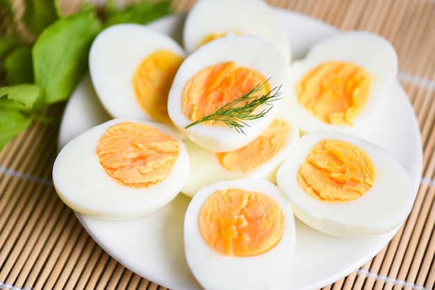 Oeufs petit-déjeuner, oeufs frais menu nourriture oeufs bouillis dans une assiette blanche décorée de feuilles vert aneth fond, coupé en deux jaunes d'oeufs pour cuisiner une alimentation saine