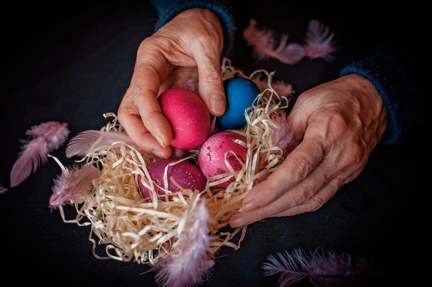 oeufs, plume et mains de femme senior sur noir