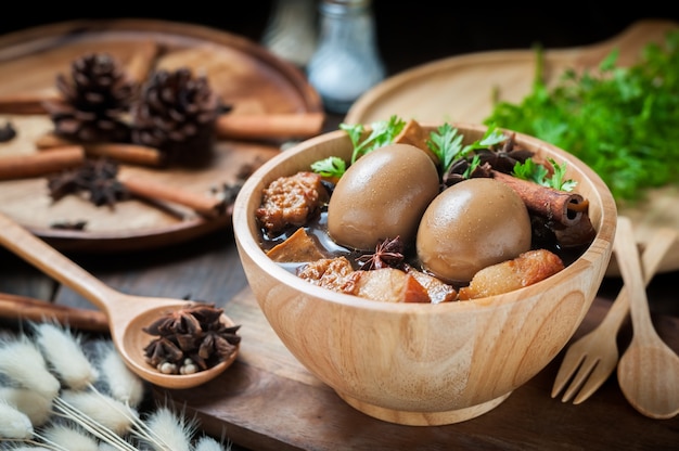 Les oeufs et le porc bouilli dans la sauce sur une table en bois.