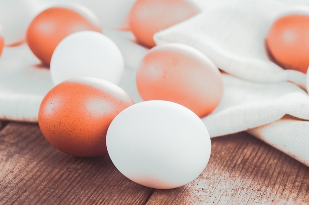 Oeufs de poule beiges et blancs sur une nappe textile sur une table en bois rustique