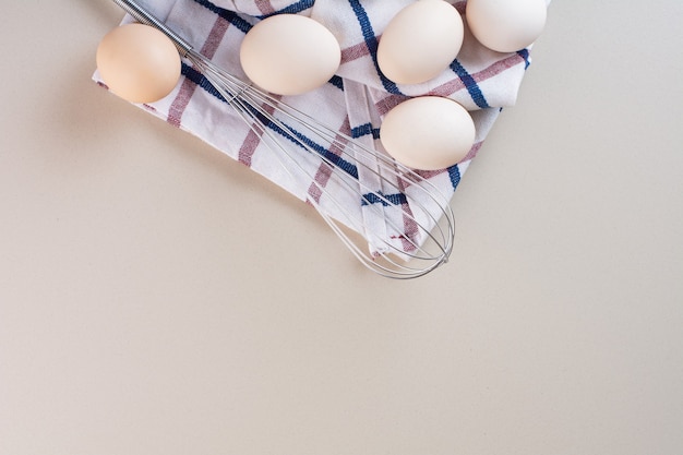 Oeufs de poule blancs crus frais placés sur une table beige.