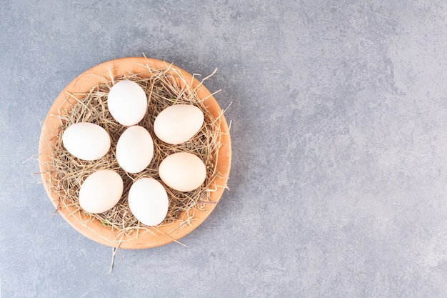 Oeufs de poule blancs crus frais placés sur une table en pierre.