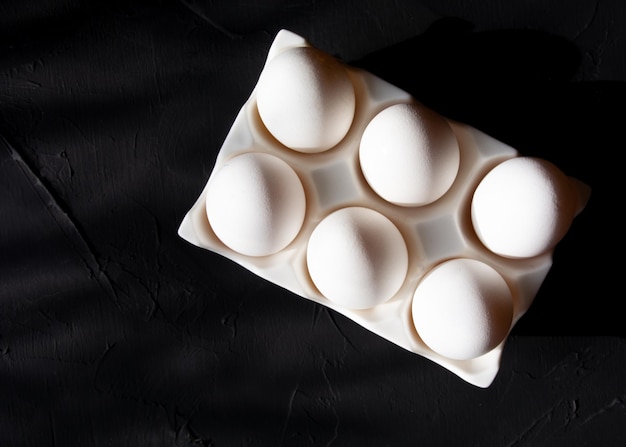 Oeufs de poule en boîte, sur fond noir, vue de dessus