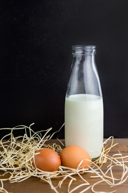 Photo oeufs de poule brune avec une bouteille de lait maison sur la table en bois