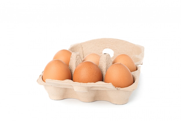 Oeufs de poule brune dans une boîte en carton isolé sur blanc