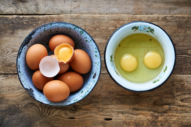 Oeufs de poule crus dans des bols métalliques sur un bois