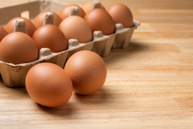 Oeufs de poule dans une boîte en carton sur une table en bois