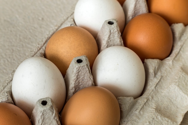 Oeufs de poule dans un carton d'oeufs en carton ouvert sur l'espace de copie de table de cuisine. Aliments biologiques sains et concept de régime alimentaire.