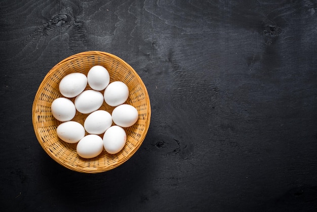 Oeufs de poule dans le panier sur fond de bois noir. Copier l'espace