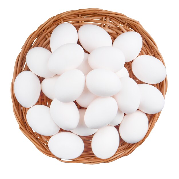 Oeufs de poule dans le panier isoler sur une surface blanche