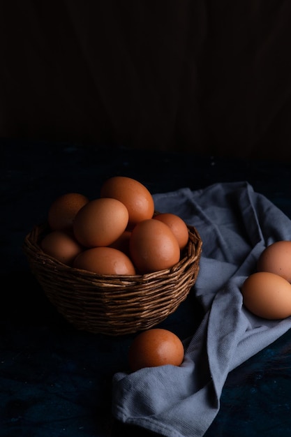 Des œufs de poule dans un panier en osier et sur une serviette