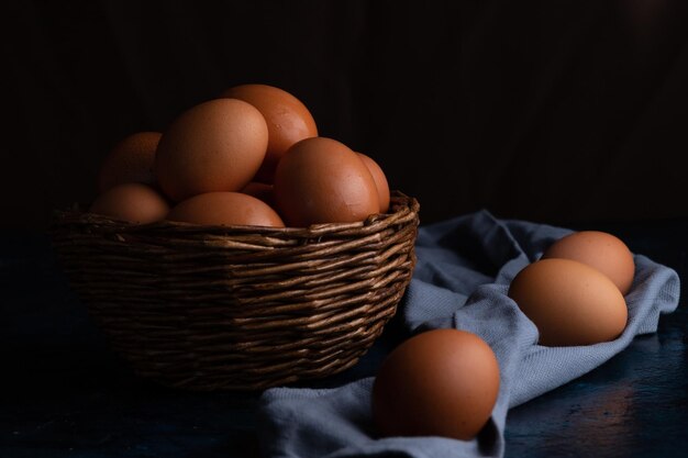 Des œufs de poule dans un panier en osier et sur une serviette