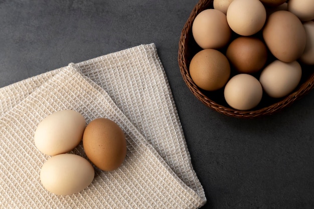 Oeufs de poule dans un panier en osier sur la table Oeufs sur un torchon