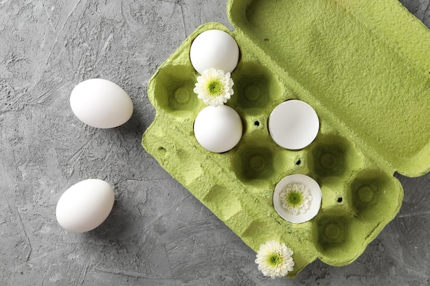 Photo des œufs de poule dans un paquet de carton vert avec des fleurs