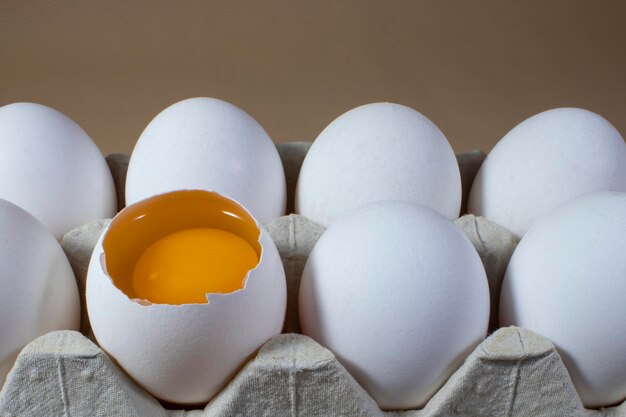 Des œufs de poule entiers et cassés dans un plateau en carton