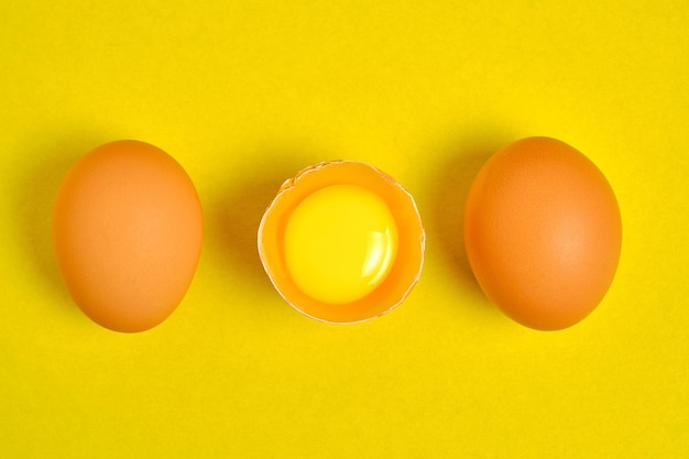 Oeufs de poule sur fond jaune cassé avec du jaune.