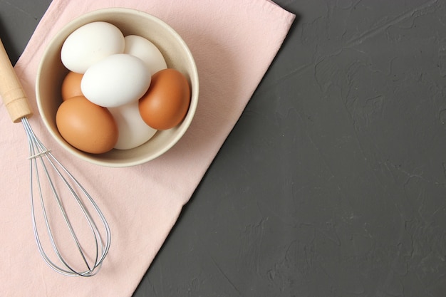 Oeufs de poule et un fouet sur la vue de dessus de table