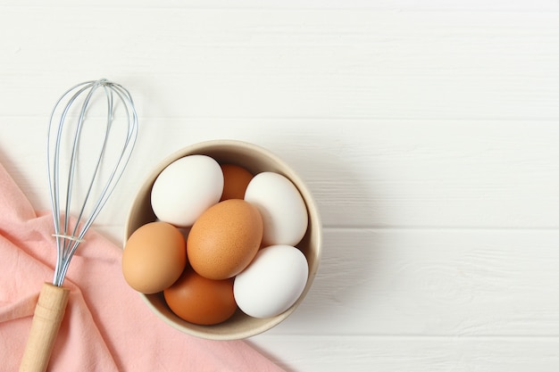 Oeufs de poule et un fouet sur la vue de dessus de table