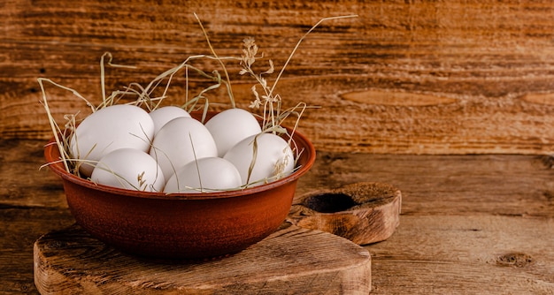 Oeufs de poule frais sur du foin sur fond de bois