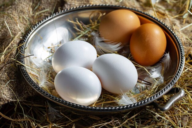 Des œufs de poule sur de l'herbe sèche sur un vieux fond