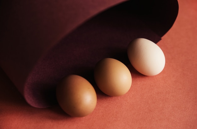 Les œufs de poule sont déposés dans une rangée sur du papier brun. Papier enroulé en spirale ou ovale. Oeufs de Pâques pour les vacances.