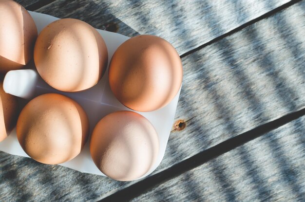 Oeufs de poule sur une vieille table en bois au soleil matinal Les ombres des stores tombent sur le fond et les oeufs