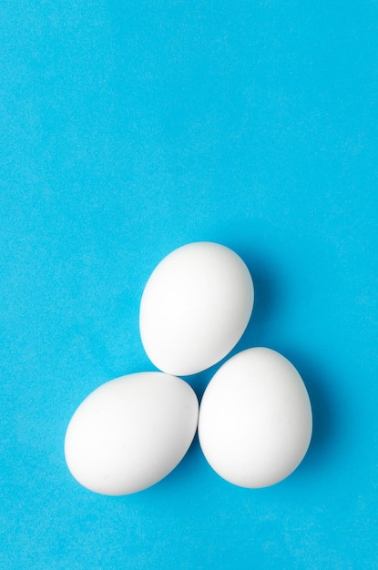 Oeufs de poulet blancs sur fond bleu gros plan