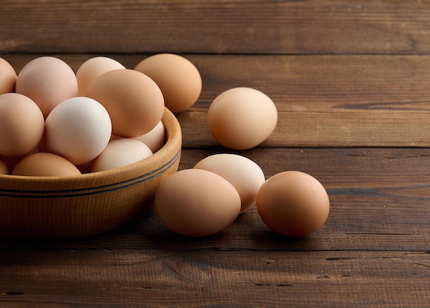 Oeufs de poulet brun frais dans une assiette ronde en bois sur la table