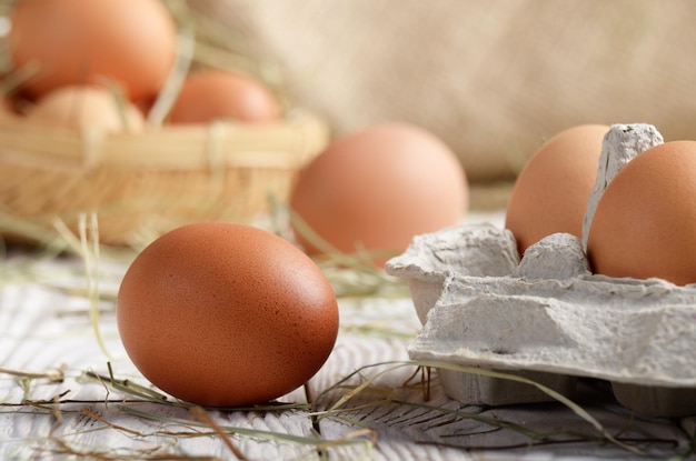 Oeufs de poulet bruns biologiques crus dans un carton de papier écologique sur une table en bois de cuisine blanche