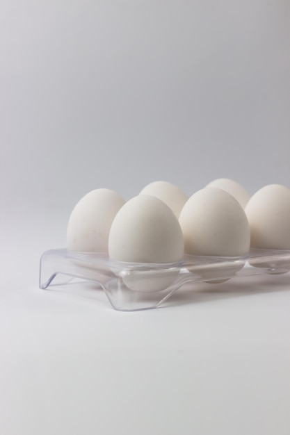 Oeufs de poulet dans un plateau sur fond blanc Ingrédients pour la cuisson