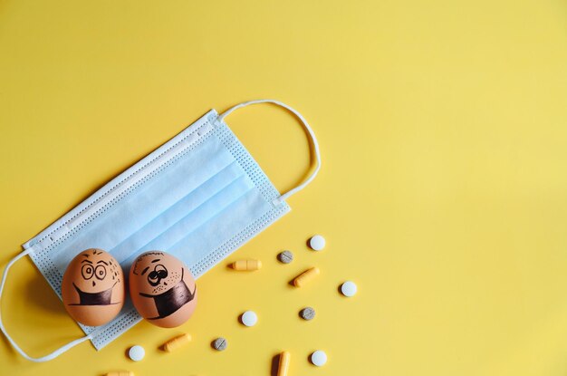 Oeufs de poulet divers avec des visages de doodle portant des masques médicaux sur fond jaune. Corona virus