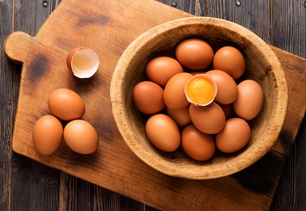 Oeufs de poulet jaunes dans un bol en bois sur une vue de dessus de texture en bois