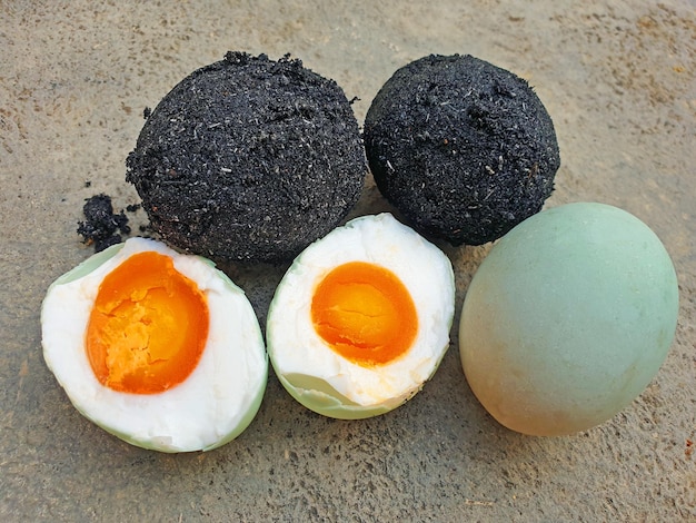 Des œufs salés maison ou Telor Asin crus et cuits sur un sol en béton gris fabriqués à partir d'œufs de canard crus