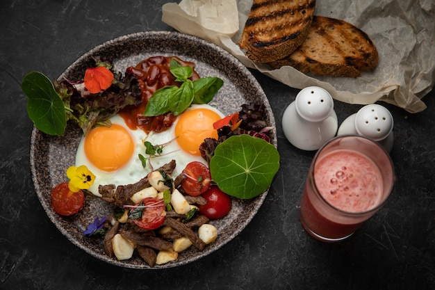 oeufs avec tomates, haricots, viande, fromage et sauce sur une assiette