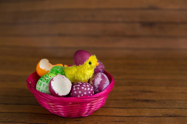 Oeufs de vacances colorés de Pâques dans le panier et l'éclosion des poussins de la coquille sur fond de bois Décoration de religion traditionnelle