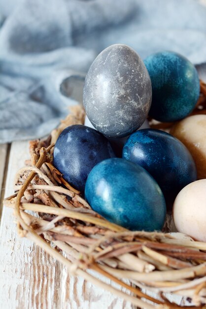 Oeufs vintage de Pâques teints avec des éraflures sur un fond gris clair dans un panier en osier. Fond élégant avec des oeufs de Pâques, moderne.