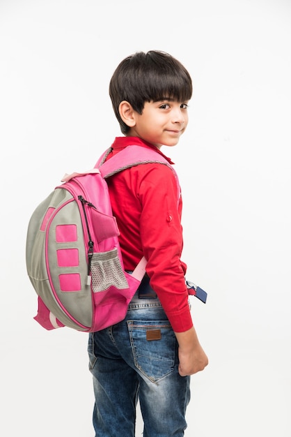 Off to School - Mignon petit garçon indien ou asiatique en chemise rouge et jean denim avec sac d'école, debout isolé sur fond blanc