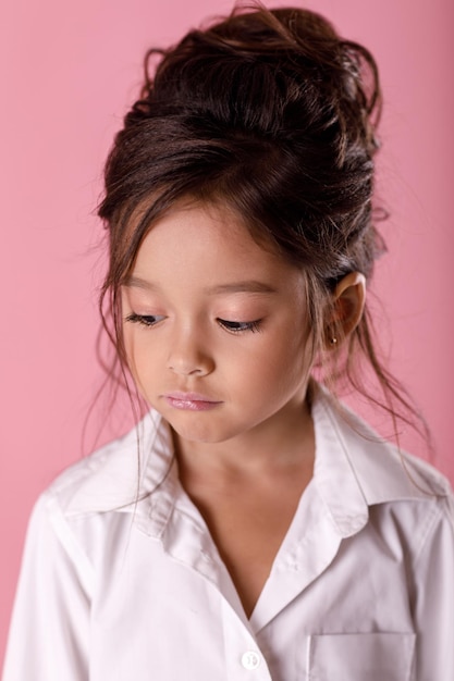 Offensé triste petite fille ennuyée en chemise blanche sur fond rose. Émotions humaines et expression faciale