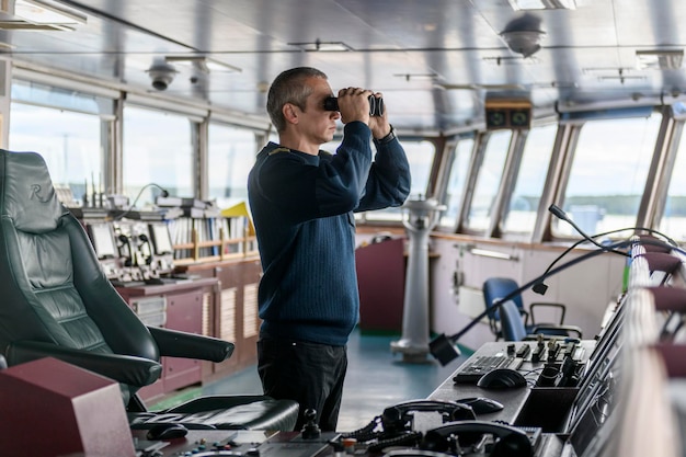 Photo officier de pont avec des jumelles sur la passerelle de navigation matelot à bord du navire navigation commerciale