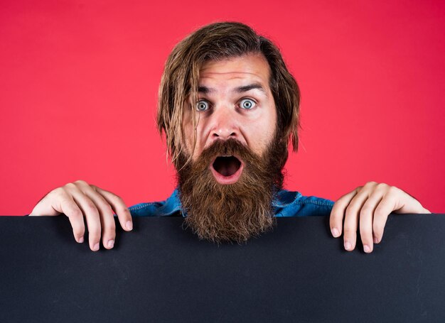 Photo offre à durée limitée dépêchez-vous concept de service de salon de coiffure de publicité homme brutal avec barbe et moustache recherche d'un lieu d'emploi pour l'espace de copie homme barbu surpris avec une feuille de papier vide