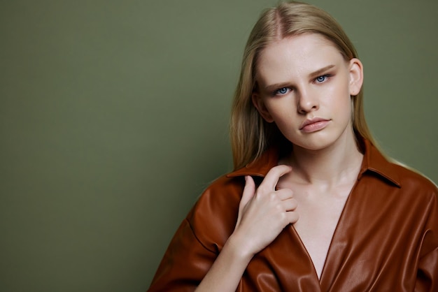 Offre de mode pour la conception de bannières Gros plan portrait d'une jeune femme confiante touchant un trench-coat en cuir regarde la caméra sur fond de mur de studio vert olive