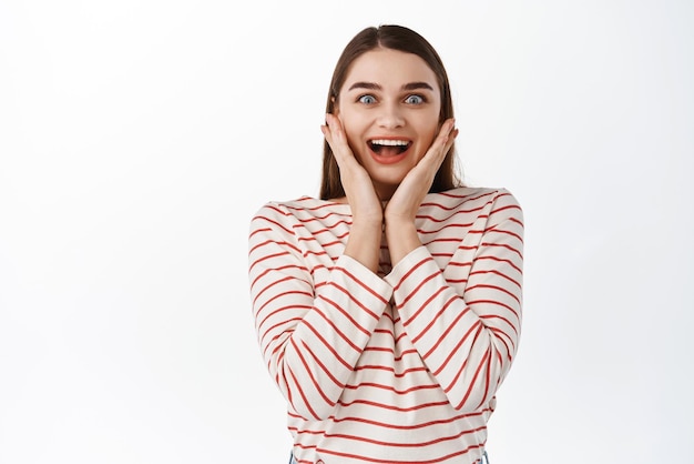 Oh mon dieu une célébrité Une fille heureuse en admiration a l'air surprise et étonnée de vérifier quelque chose de génial Je ne peux pas croire que ses propres yeux sourient et regardent étonné debout sur fond blanc