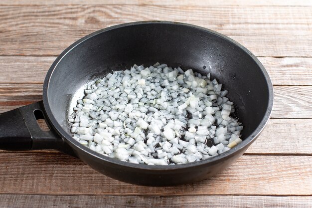 Oignon haché dans une poêle à frire pour la cuisson de lobio de haricots verts aux légumes et à la tomate. Recette pas à pas. Nourriture saine.