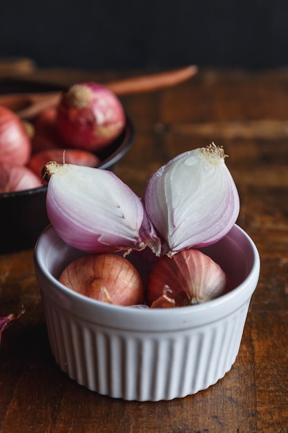 Oignon rouge frais dans un bol sur table en bois.