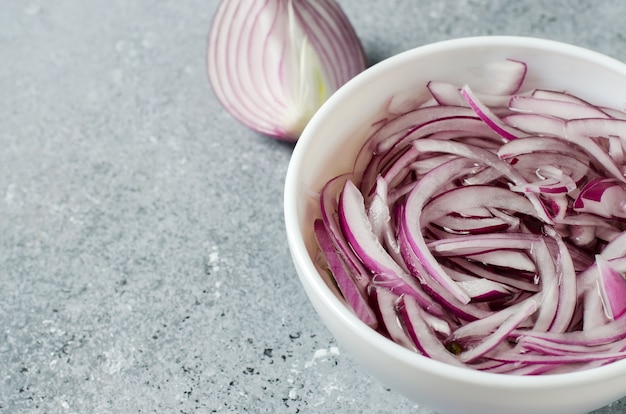 Oignon rouge haché mariné au vinaigre dans une assiette blanche.