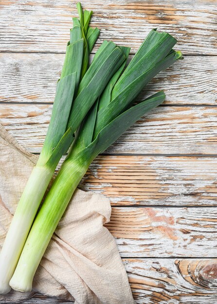 Oignon sultan poireau vert sur table en bois blanc