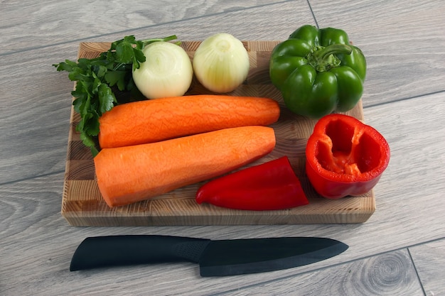 Oignon tranché et poivron sur une planche de cuisine avec persil et carottes