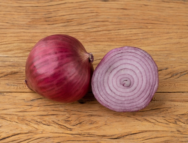 Oignon violet ou rouge et demi sur table en bois.